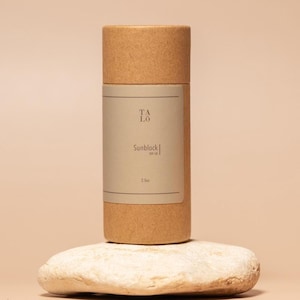 May include: A brown cardboard tube with a white label that says "Talo Sunblock SPF 30 2.5oz". The tube is sitting on a light gray rock.