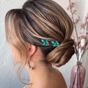 Stunning silver hair pin adorned with radiant green crystals, crafted in a delicate design to bring a pop of color and elegance to any updo or special occasion hairstyle.