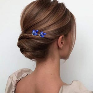 Bridal updo adorned with elegant blue crystal hair pins, featuring vibrant deep blue crystals that add a pop of color and sparkle, perfectly complementing the bridal sophisticated hairstyle