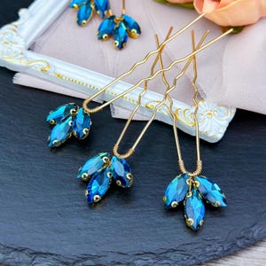 Stunning blue crystal hair pin in gold, adorned with vibrant deep blue crystals set in a luxurious gold alloy, ideal for enhancing updos and formal hairstyles with a chic pop of color.