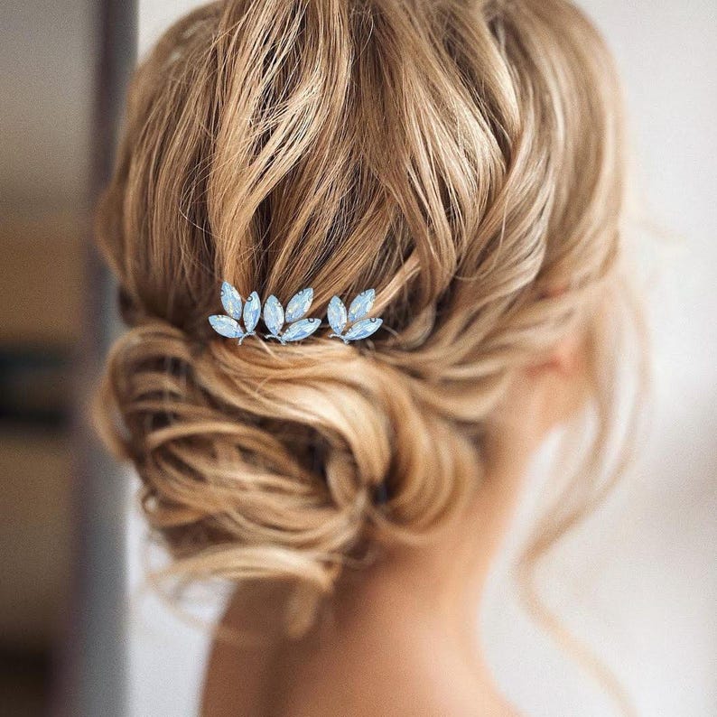 Bridal updo adorned with elegant blue opal hair pins, featuring sparkling opal and clear crystals with deep blue and green rhinestones, adding a touch of sophistication and color to the bridal hairstyle.