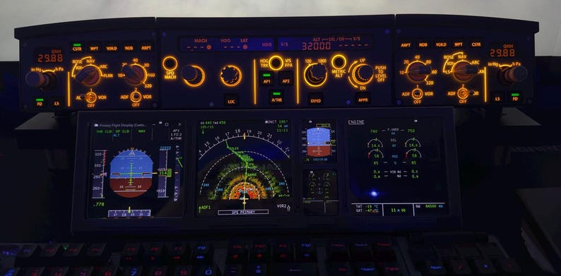 May include: A detailed view of an aircraft cockpit panel with multiple illuminated displays and controls. The displays show various flight data, including altitude, speed, and engine performance. The panel is dark with orange and blue lighting.