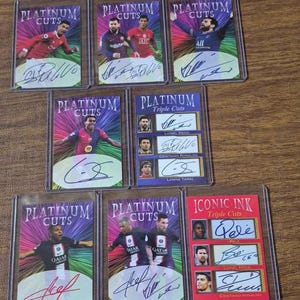May include: A collection of eight rectangular sports trading cards in protective plastic sleeves. The cards feature football players, some with autographs, and include Platinum Cuts and Iconic Ink branding with colourful, radiant background designs.