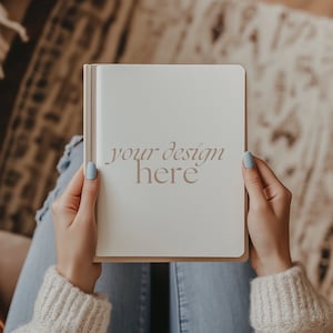May include: A person holding a blank white notebook with the text "your design here" written on it.