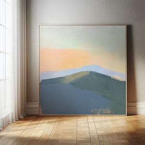 以下が含まれることがあります： 柔らかく落ち着いた色合いの抽象的な風景画。絵画は、薄い青色の空と桃色の夕焼けを背景に、山脈を描いています。