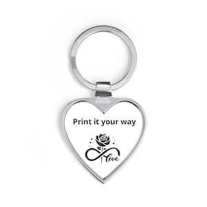 May include: A heart-shaped silver keychain with a white center insert. The insert features the black text Print it your way above a graphic of a rose blooming from an infinity symbol with the word love written in a cursive script font.