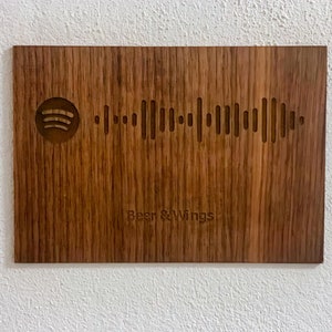 Op de afbeelding: Een houten plaquette met een Spotify-logo en een barcode, en de tekst "Beer & Wings" erop gegraveerd.