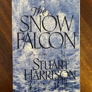 May include: A book cover for "The Snow Falcon" by Stuart Harrison. The cover features a winter forest scene in shades of blue and white. The title and author's name are in black, with "Unabridged" and "Brilliance Audio" at the top.