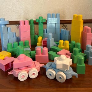Pode incluir: Uma coleção de blocos de construção de plástico coloridos em várias formas e tamanhos. Os blocos são principalmente azuis, rosa, verdes e amarelos, com alguns blocos que se assemelham a torres e veículos. Um brinquedo divertido para crianças.