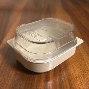 Op de afbeelding: Een beige magnetronbestendige voedselcontainer met een doorzichtig deksel. Op het deksel staat de tekst "For Microwave Use Only". De container is rechthoekig met afgeronde hoeken.