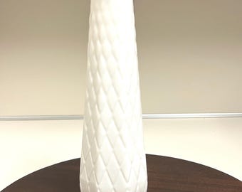 May include: White milk glass vase with a diamond pattern. The vase has a scalloped rim and a rounded base.