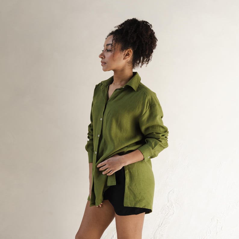 May include: A long-sleeved, olive green linen shirt with a collared neckline and button closure. The shirt is loose-fitting and has a relaxed silhouette.