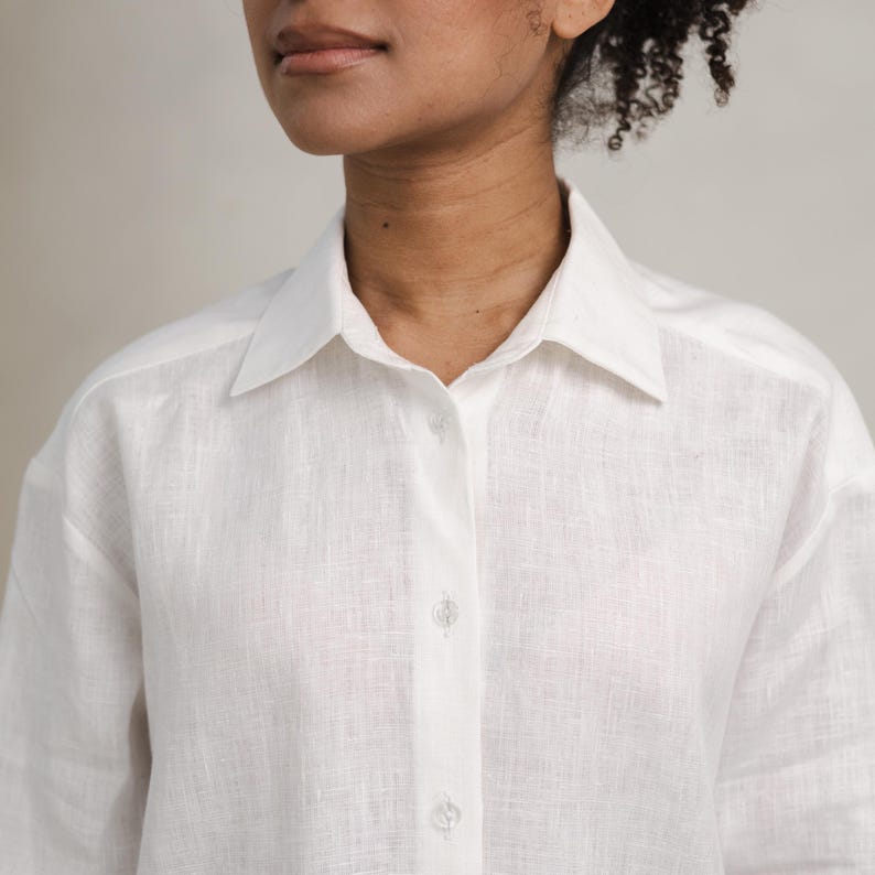 May include: A white linen shirt with a button-up front and long sleeves.