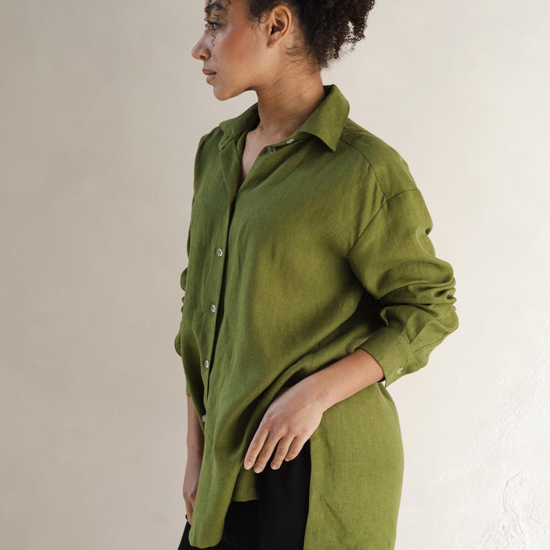 May include: A long-sleeved, green linen shirt with a button-down collar and a side slit. The shirt is loose-fitting and has a relaxed silhouette.
