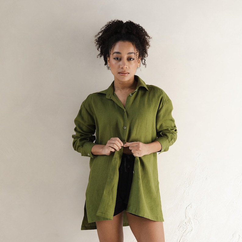 May include: A long-sleeved, olive green linen shirt with a collared neckline and button closure. The shirt is loose-fitting and has a relaxed silhouette.