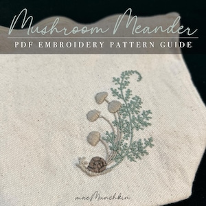 May include: A close-up of a white fabric with a green and brown embroidered design of mushrooms and a snail. The text "Mushroom Meander PDF EMBROIDERY PATTERN GUIDE" is at the top of the image. The text "mae/Munchkin" is at the bottom of the image.