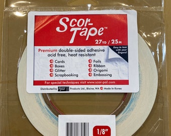 May include: A roll of Scor-Tape double-sided adhesive tape in a clear plastic package. The label is red and white, with the text "Scor-Tape" and "1/8" printed on it. The tape is 1/8 inch wide and is acid-free and heat resistant.