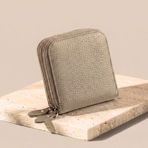 Storm gray leather jewelry wallet on a decorative stone base, highlighting the soft-touch natural cowhide material.