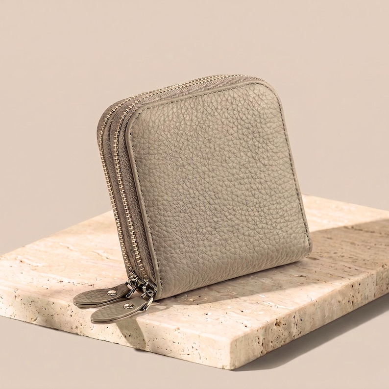 Storm gray leather jewelry wallet on a decorative stone base, highlighting the soft-touch natural cowhide material.
