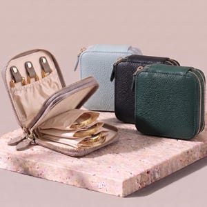 Open leather jewelry bag showing the smart interior layout with rings and chains organized in soft, snag-free compartments.
