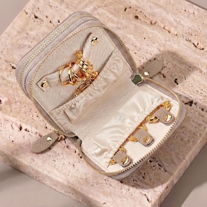 Detailed view of the top compartment with 3 leather snaps and an elastic pocket for tangle-free necklace storage.