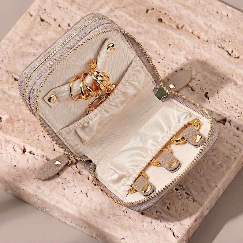 Detailed view of the top compartment with 3 leather snaps and an elastic pocket for tangle-free necklace storage.