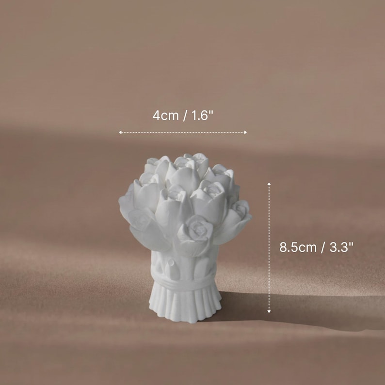 A white plaster sculpture of a rose bouquet used as a unique and aesthetic ring holder for multiple gold rings.