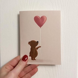 L'amour est dans l'air - Jolie carte avec un petit ours tenant un ballon coeur - Carte illustrée simple pour votre proche