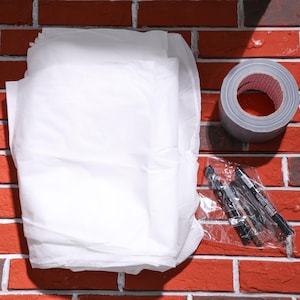 May include: A white fabric sheet, a roll of gray duct tape, and a package of black permanent markers on a red brick background.