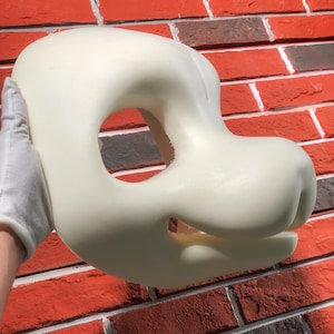 May include: A white foam blank fursuit head with a large, open mouth and a small, round nose. The head is designed for a furry character.
