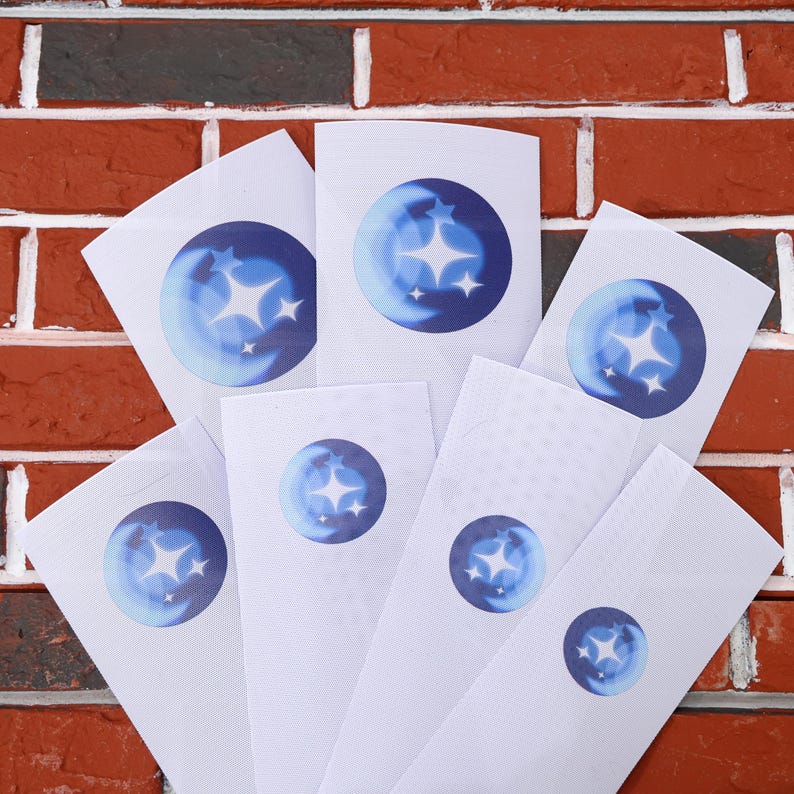 May include: Seven white cards with a blue circle containing a crescent moon and three white stars. The cards are arranged in a fan shape against a brick wall background.