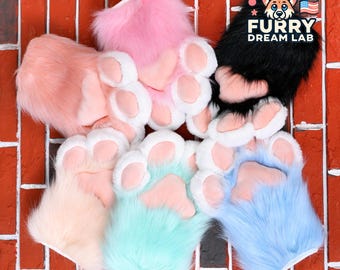 May include: Six pairs of furry paw hand puppets in various colors, including pink, peach, light blue, turquoise, and black. The puppets have white paw pads and are arranged on a red brick background. The text "FURRY DREAM LAB" is visible in the upper right corner of the image.