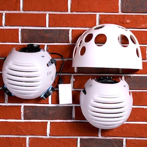 May include: Three white spherical lighting accessories with a grid pattern and a circular pattern of holes. The accessories are mounted on a brick wall.