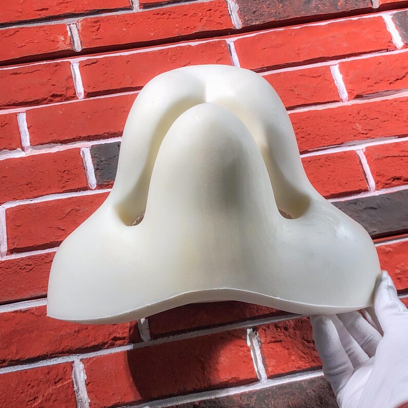 May include: White foam nose contouring tool for makeup application. The tool has two indentations for the nostrils and a raised center for the bridge of the nose.