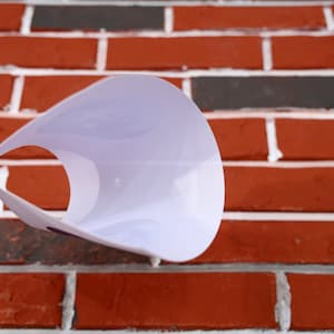 May include: White plastic cone-shaped pet collar with a textured surface. The collar is designed to prevent pets from licking or scratching wounds.