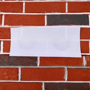 May include: A white rectangular sign with two semi-circles on it, hanging on a brick wall.
