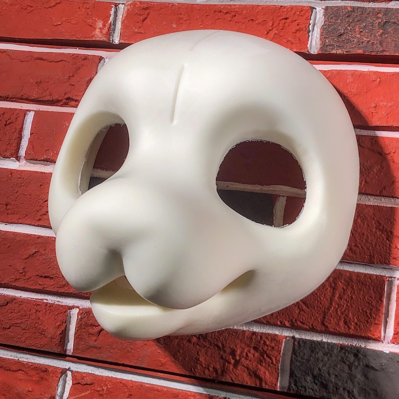 May include: A white unfinished furry animal mask with eye and mouth openings. The mask is made of a smooth, hard material and is ready for painting and furring.