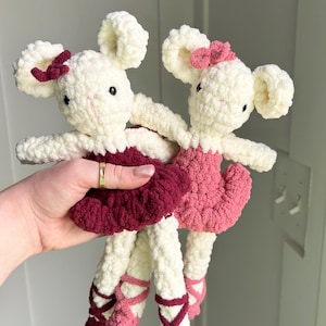 Puede incluir: Dos muñecas de ratón hechas a mano con ganchillo. Los ratones son blancos con orejas grandes y redondas y pequeños lazos. Llevan tutús de ballet en tonos rosa y burdeos, con zapatillas de ballet a juego. Las muñecas son suaves y afelpadas.