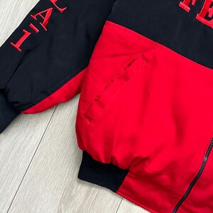 May include: A black and red jacket with the word "AFTER" embroidered in red on the upper back. The jacket has a black zipper and black cuffs. The sleeve has the word "LIFE" embroidered in red.