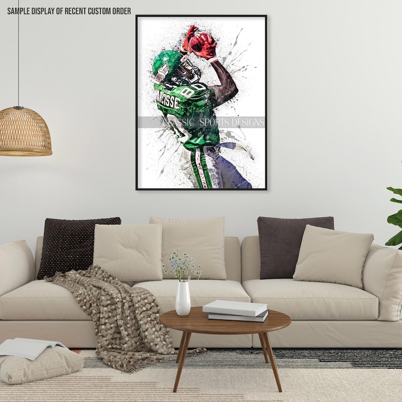 May include: A watercolor painting of a football player in a green and white uniform catching a red football. The background is white with splatters of paint.