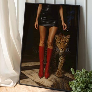 May include: Framed art print featuring a woman in a black dress and red boots, holding a cigarette, with a leopard. The artwork has a dark, dramatic aesthetic, with a focus on fashion and wildlife.