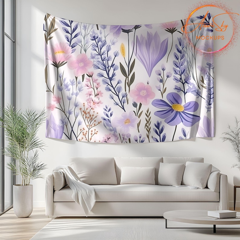 Op de afbeelding: Een witte wandkleed met een bloemenpatroon met roze, paarse en blauwe bloemen. De wandkleed hangt aan een witte muur boven een witte bank.