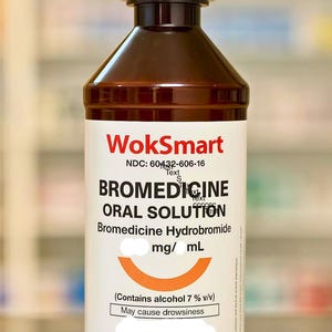 Può includere: Una bottiglia marrone di medicinale "BROMEDICINE ORAL SOLUTION" con un'etichetta bianca. L'etichetta include il marchio "WokSmart" e il testo "Può causare sonnolenza". La bottiglia ha un tappo bianco e contiene 473 ml di liquido.