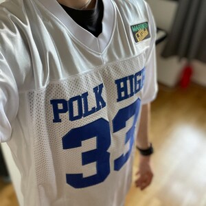 May include: White jersey with blue lettering that says "POLK HIGH" and the number "33". The jersey has a small patch that says "MARRIED TO A REAL ONE".