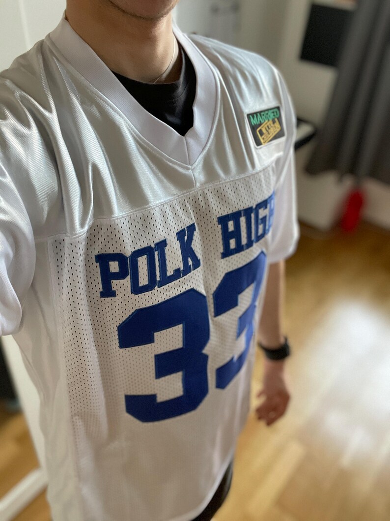 May include: White jersey with blue lettering that says "POLK HIGH" and the number "33". The jersey has a small patch that says "MARRIED TO A REAL ONE".