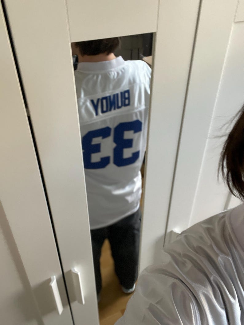 May include: White jersey with blue lettering and the number 33 on the back. The lettering says "Younus".