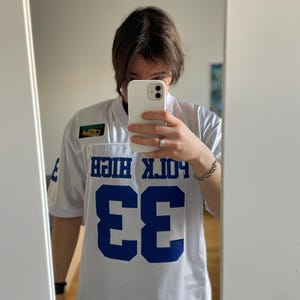 May include: White jersey with blue lettering and a number 33 on the front. The jersey says "Polk High" on the back.