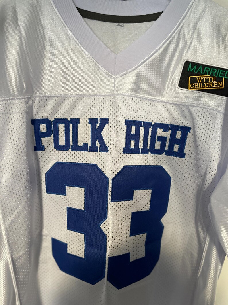 May include: White football jersey with blue lettering that reads "POLK HIGH" and the number "33". A small patch on the right shoulder reads "MARRIED WTH CHILDREN".