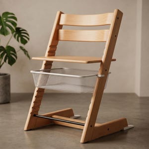 Könnte beinhalten: Ein hellfarbiger Hochstuhl aus Holz mit einem Tablett und einem Metallkorb zur Aufbewahrung. Der Stuhl hat eine Fußstütze und eine Rückenlehne mit drei horizontalen Lamellen. Der Stuhl ist für ein Kind konzipiert.