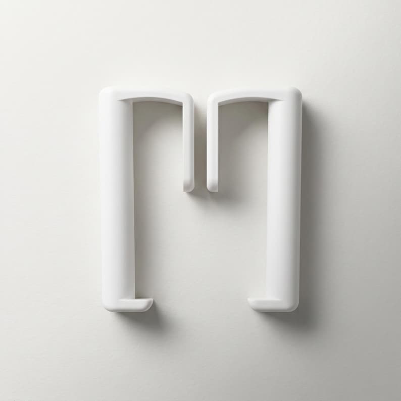 May include: Two white, minimalist plastic coat hangers. Each hanger has a cylindrical vertical support and a curved top with a hook. The hangers are set against a plain white background.
